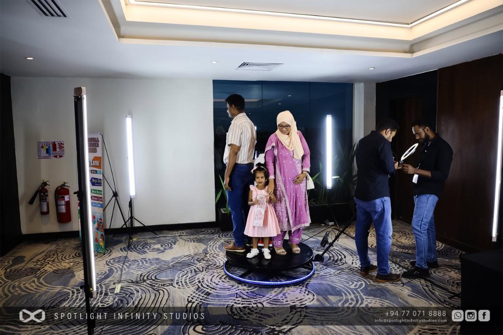 Family posing on a 360 video booth platform with LED lighting at an indoor event
