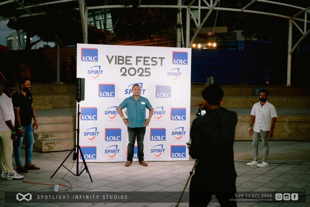 Guest posing at a branded photo booth backdrop during an outdoor event