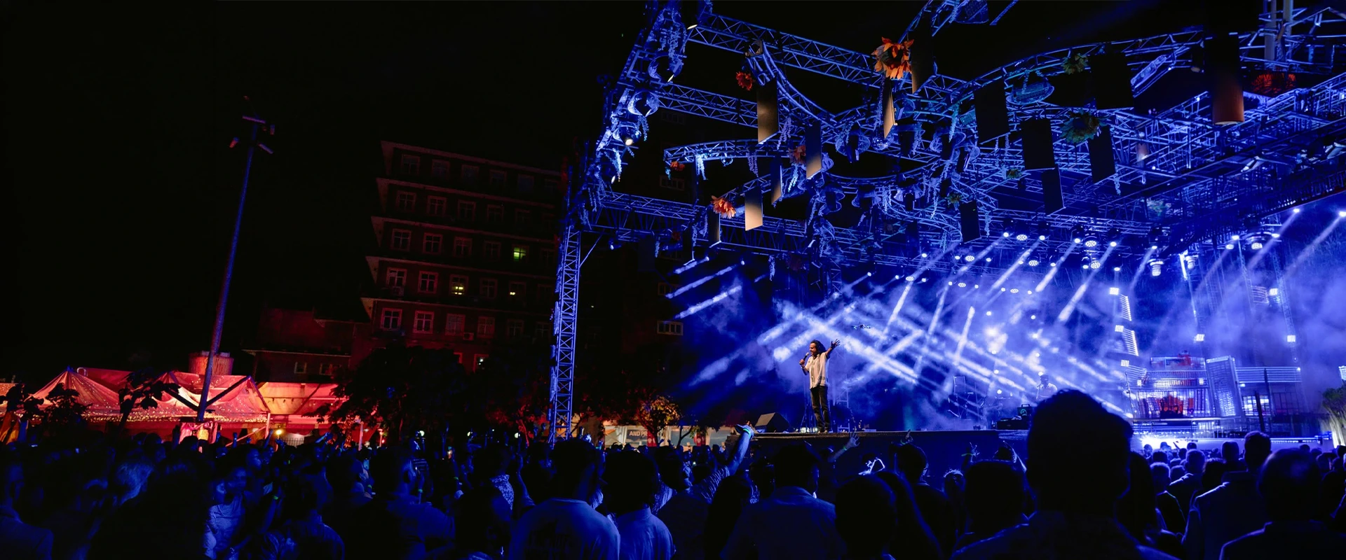Night concert stage with performer and crowd under blue lights